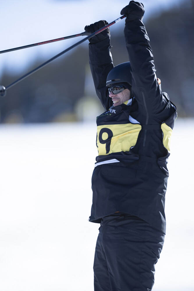 Een skiër juicht met beide armen omhoog.